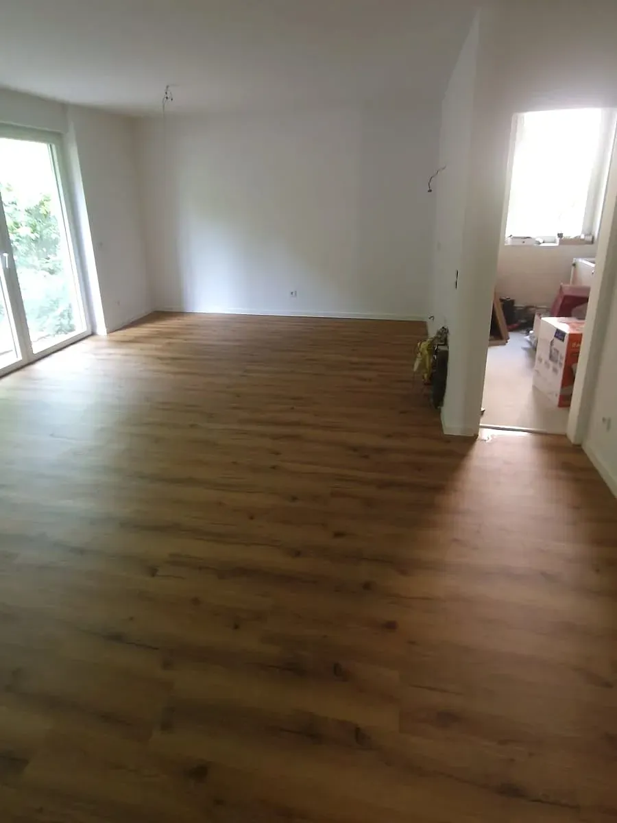 Wohnzimmer mit neuem Vinyl in dunkler Eiche, Wände und Sockelleisten erneuert in Münster